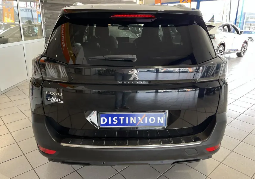Vue arrière d'un Peugeot 5008 noir métallisé exposé en showroom avec feux arrière LED 3D et logo central chromé.