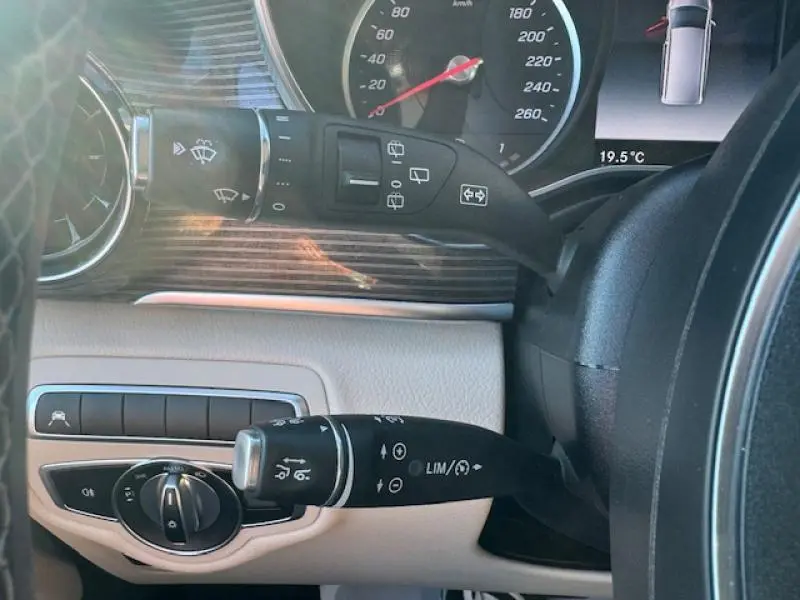 Détail du tableau de bord beige et bois du Mercedes Classe V 250 d avec commandes au volant et compteur visible.