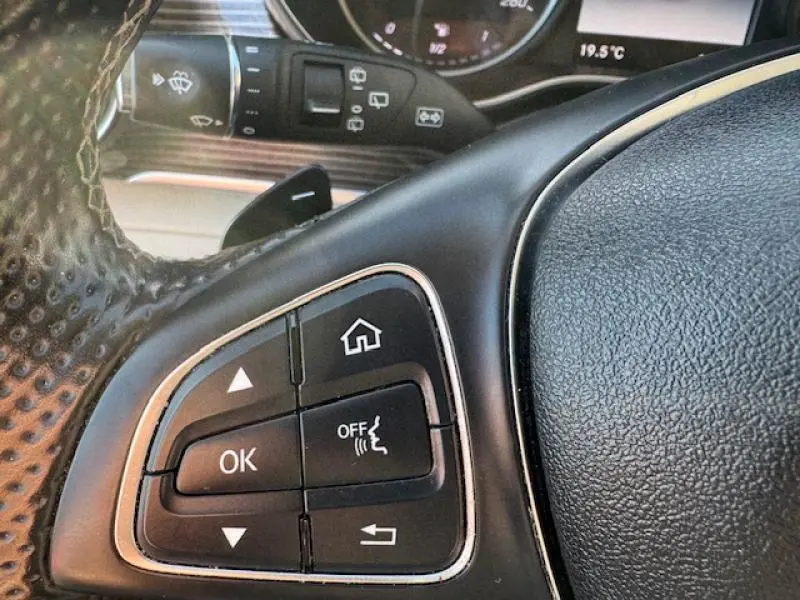 Gros plan sur les commandes gauche du volant cuir noir du Mercedes Classe V blanc cristal de roche métallisé de 2019