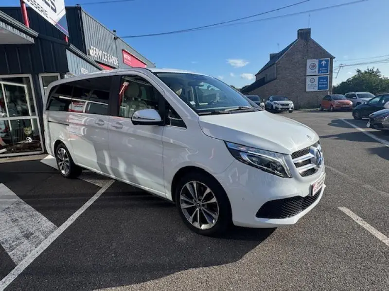 Mercedes Classe V 250 d Long Avantgarde blanc cristal de roche, vue 3/4 avant droit, stationné devant un garage.