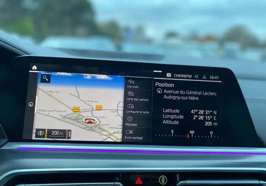 Écran de navigation intérieur du BMW X5 blanc 2022, affichant la carte et la position GPS sur le tableau de bord.