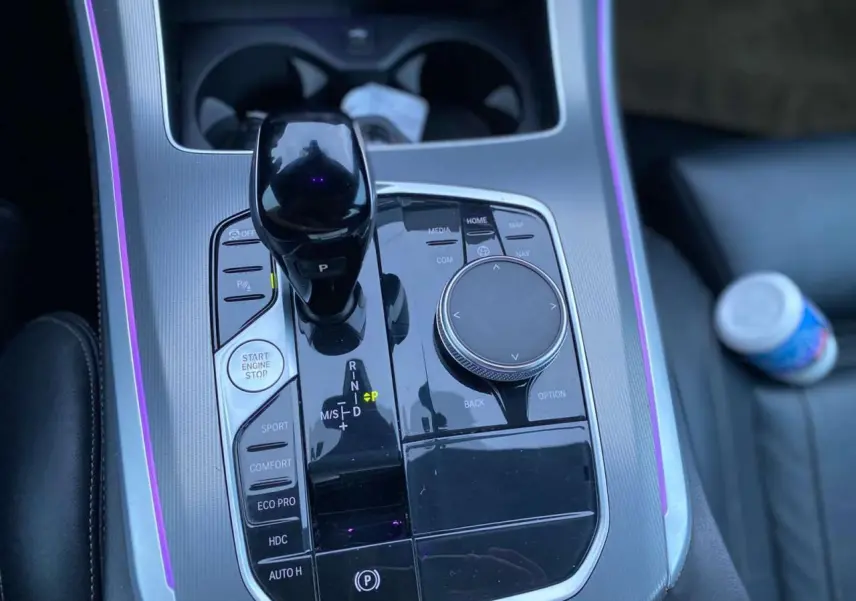 Vue rapprochée de la console centrale noire du BMW X5 blanc 2022, avec levier de vitesses et commandes de conduite.