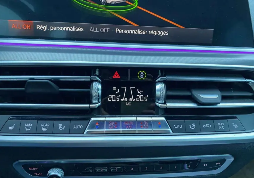 Vue rapprochée du tableau de bord du BMW X5 blanc 2022, affichant les commandes de climatisation et ventilation.