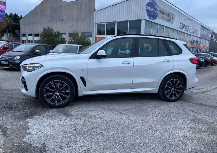 BMW X5 xDrive 30d blanc en vue profil côté gauche, avec jantes M Sport noires et détails sportifs visibles.