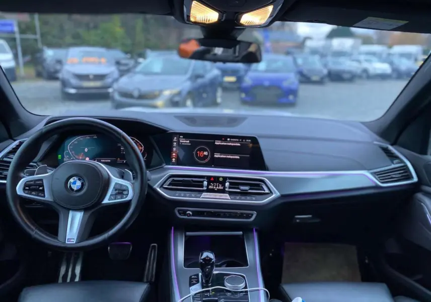 Intérieur du BMW X5 xDrive 30d 2022, tableau de bord et volant M Sport avec éclairage d'ambiance violet.