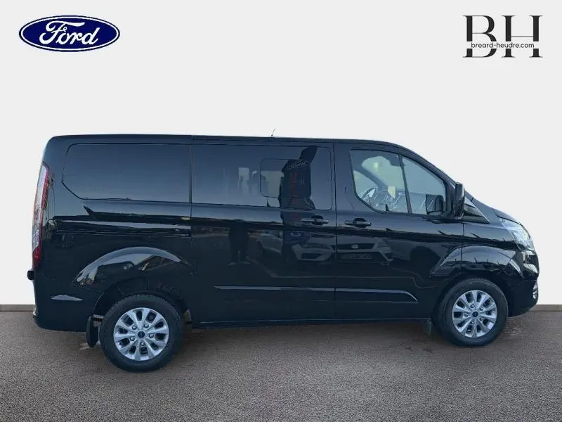 Profil droit du Ford Transit Custom Fourgon noir Agate métallisé, avec jantes alu et vitres arrière surteintées.