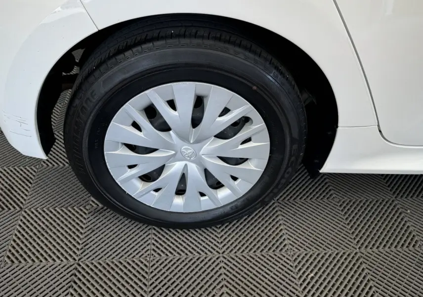 Gros plan sur la roue avant gauche blanche d'une Toyota Yaris hybride 2022 avec enjoliveur argenté et carrosserie blanche.