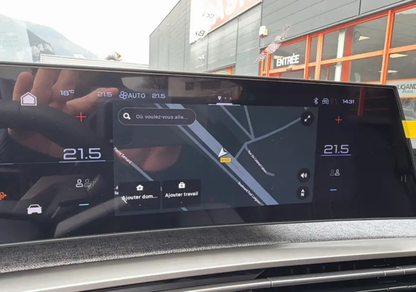 Écran tactile central du tableau de bord du Peugeot 3008 Hybrid 2025 affichant la navigation GPS et la climatisation à 21,5°C.