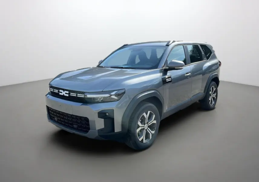 Vue 3/4 avant du Dacia Bigster gris schiste, SUV hybride avec jantes alu 17 pouces et barres de toit visibles.