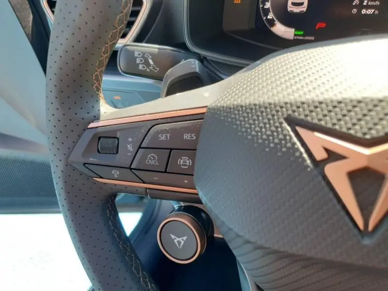 Gros plan sur le volant cuir perforé gris du CUPRA Formentor bleu, avec commandes multifonctions et logo CUPRA visible.