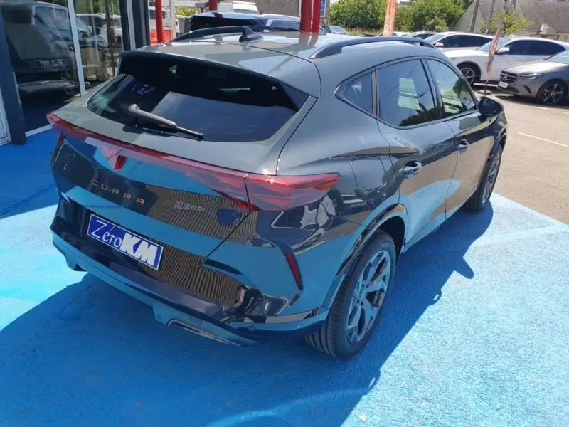 Vue 3/4 arrière droite d'une CUPRA Formentor bleu Fjord avec feux arrière LED et jantes alu sur sol bleu.