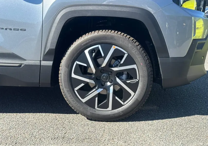 Gros plan sur la roue avant droite du Jeep Compass Yosemite gris avec jante alu noire et grise, partie latérale visible.