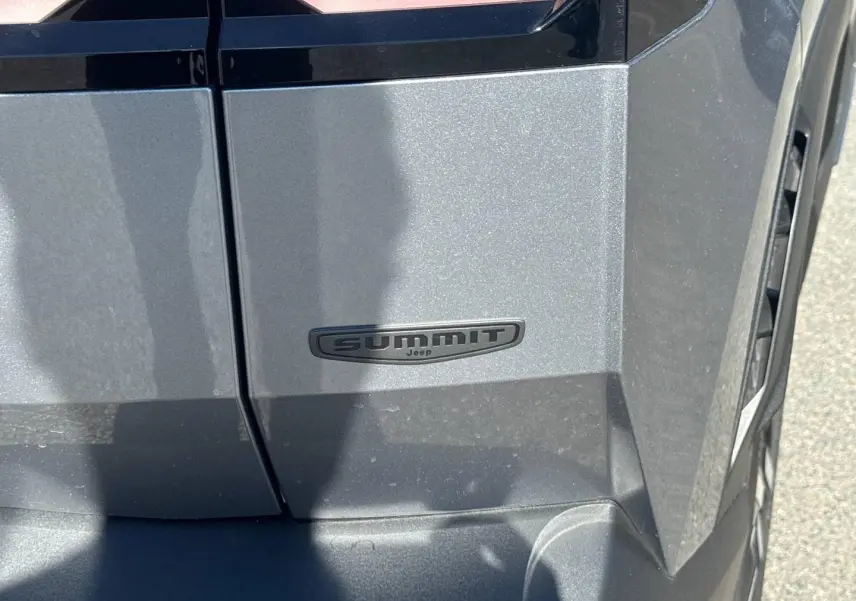 Gros plan sur l’emblème Summit côté droit d’un Jeep Compass 2026 gris Yosemite avec toit noir.
