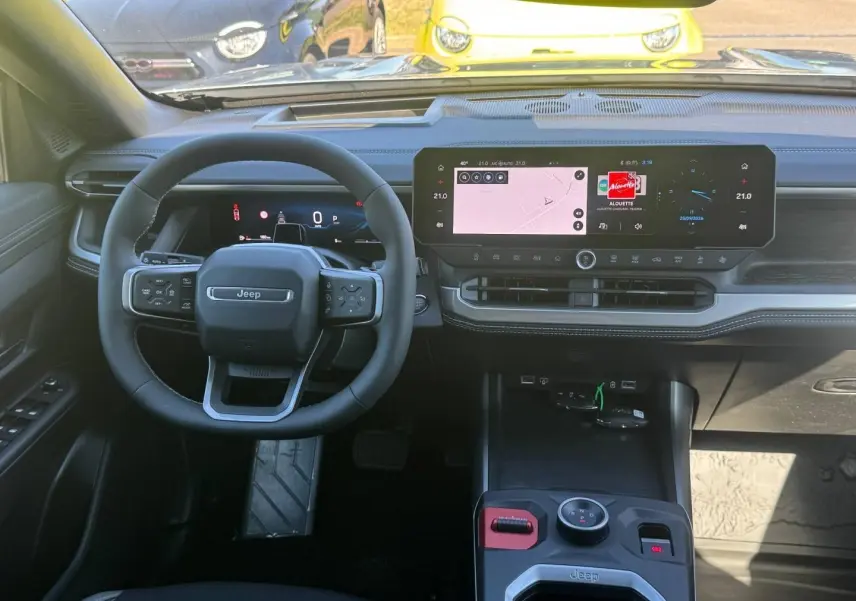 Vue intérieure frontale du tableau de bord du Jeep Compass 2026, avec écran tactile large et volant multifonctions noir.
