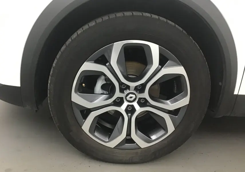 Gros plan sur la roue avant gauche du Renault Captur blanc nacré avec jante alliage 18 pouces au design moderne.