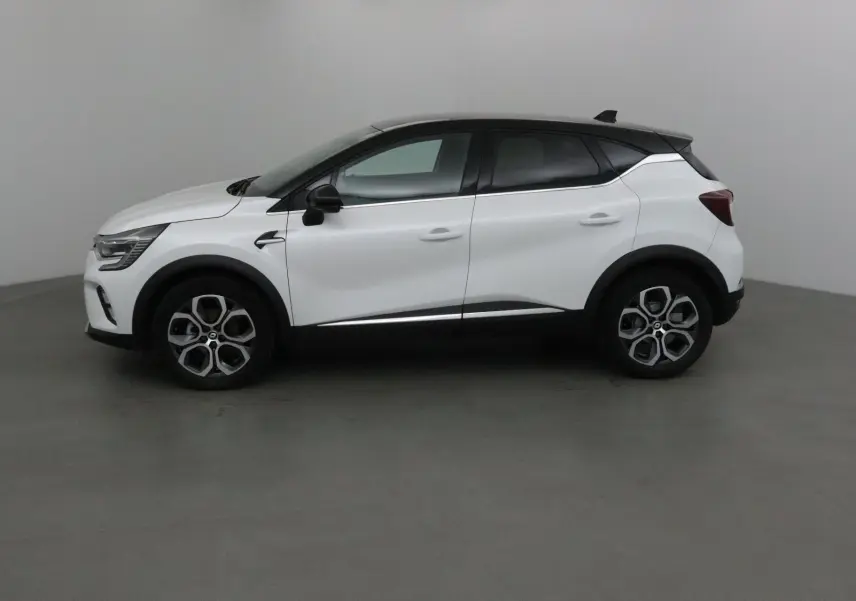 Profil côté gauche d'un Renault Captur blanc nacré avec toit noir, jantes alliage et lignes modernes.