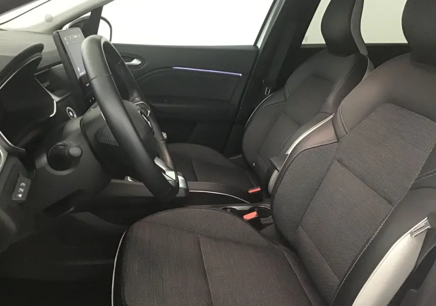 Intérieur du Renault Captur 2024 vu côté conducteur, sièges noirs avec surpiqûres claires et écran tactile vertical.