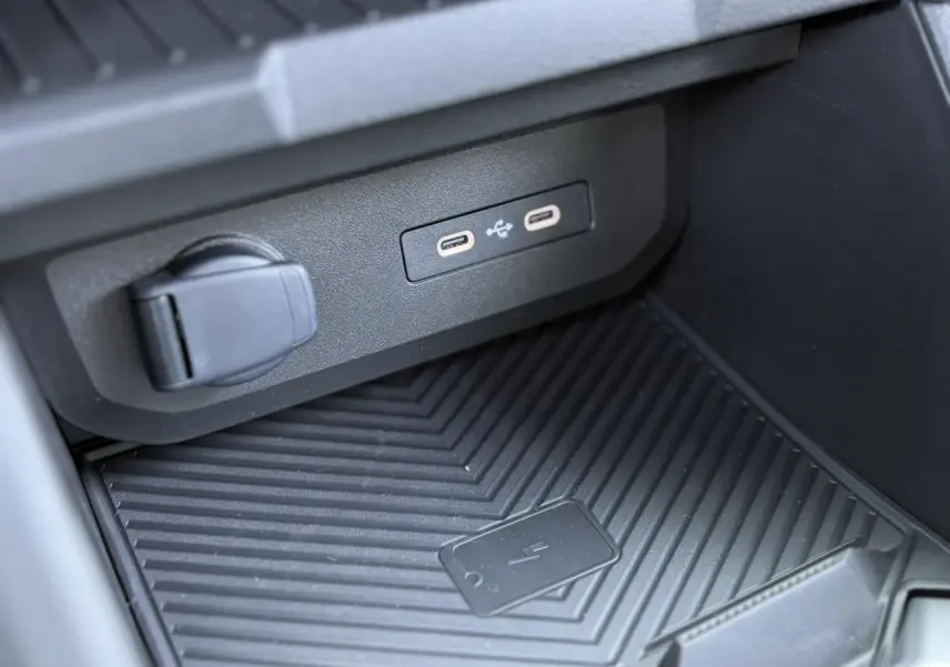 Gros plan sur la console centrale du Dacia Duster 2025 montrant les ports USB-C et le chargeur à induction noir.