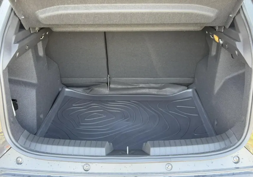 Vue intérieure du coffre ouvert du Dacia Duster noir nacré 2025, montrant le tapis de protection en caoutchouc.