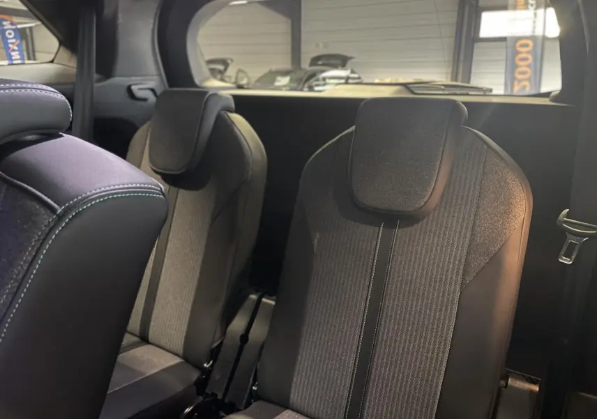 Sièges arrière indépendants noirs et gris du Peugeot 5008 2024 vus de côté droit dans un intérieur sombre