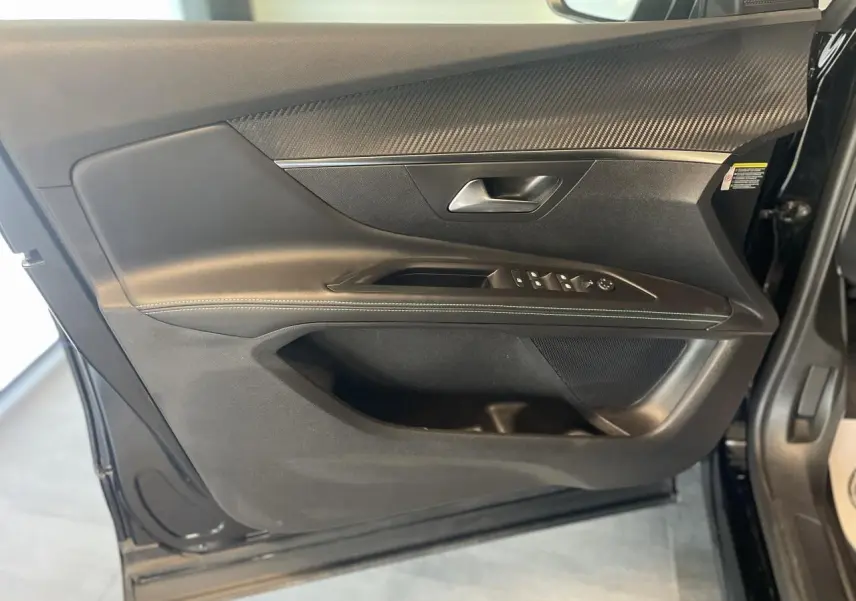 Porte côté gauche ouverte du Peugeot 5008 noir métallisé, montrant les commandes de vitres et insert décor carbone.