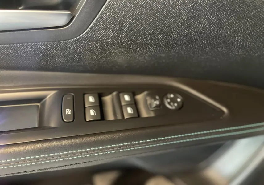 Gros plan sur la commande des vitres côté conducteur du Peugeot 5008 2024 avec surpiqûres bleues sur panneau de porte noir.