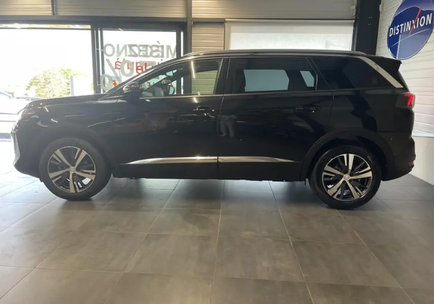 Peugeot 5008 noir métallisé vue de profil côté gauche, avec jantes alliage bi-ton et barres de toit profilées.