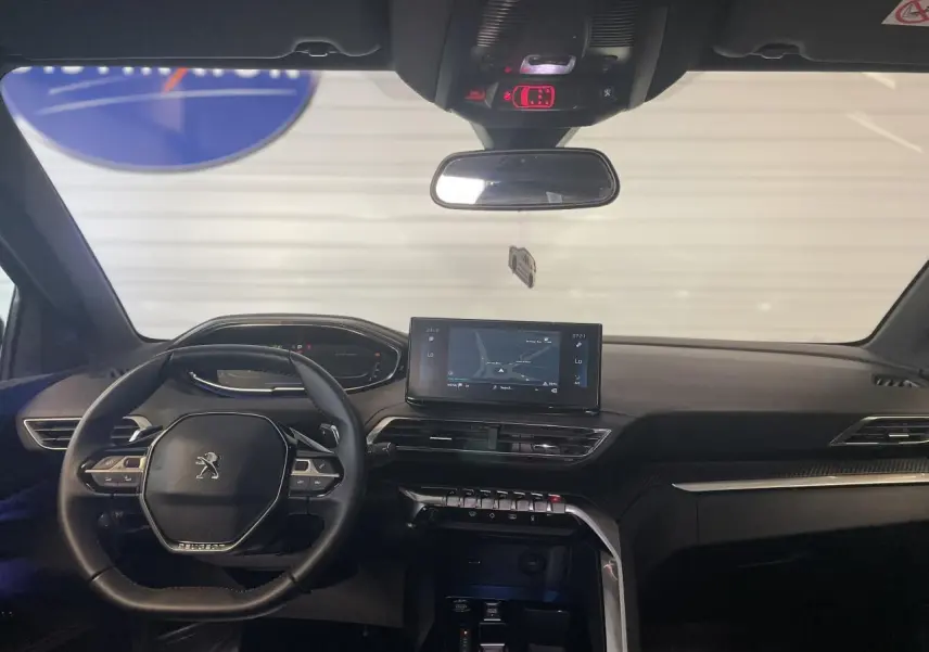 Intérieur noir du Peugeot 5008 2024, vue frontale du tableau de bord avec écran tactile et volant compact multi-fonctions.