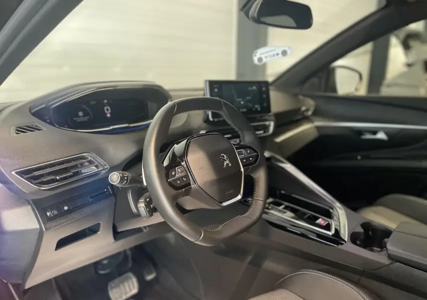 Intérieur du Peugeot 5008 2024 vu côté conducteur, volant compact et tableau de bord numérique avec écran tactile central.