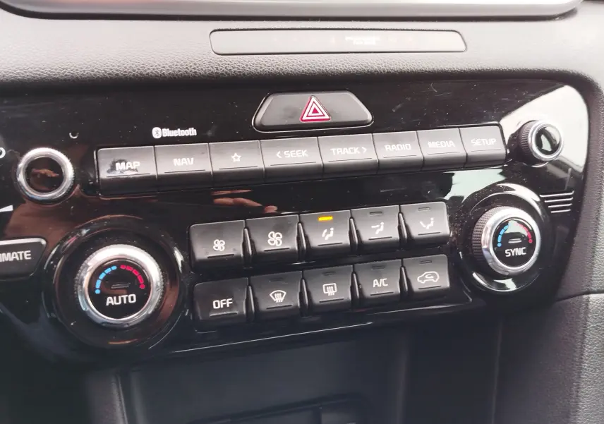 Gros plan sur la console centrale noire du Kia Sportage 2022, montrant les commandes de climatisation et multimédia.