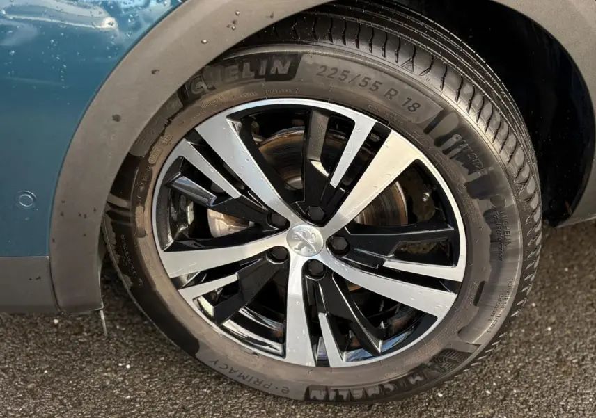 Gros plan sur la jante alliage 18 pouces bi-ton noir et argent du côté gauche d'un Peugeot 3008 Bleu Célèbes.
