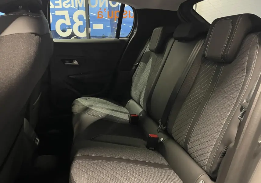 Vue latérale intérieure des sièges arrière gris foncé avec surpiqûres claires du Peugeot 208 Allure 2025.