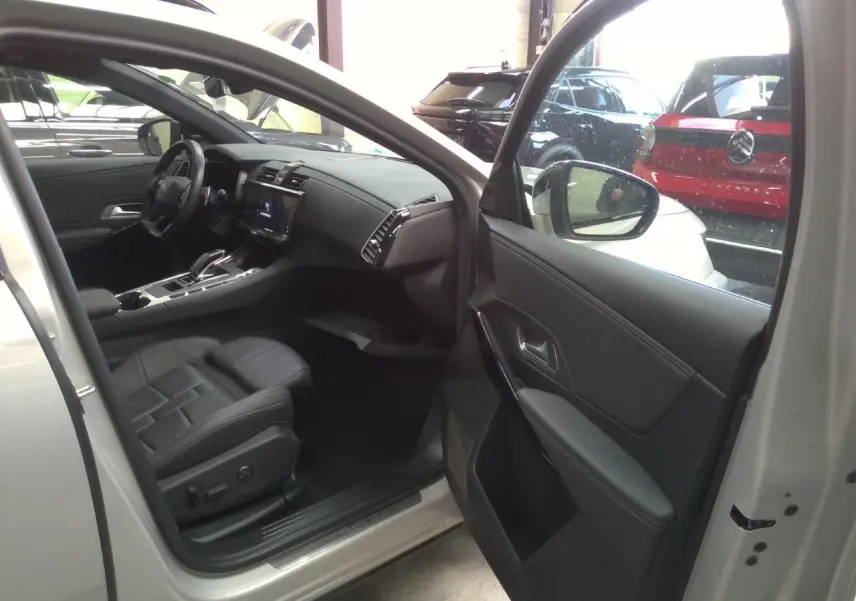 Vue intérieure côté conducteur du DS7 Cristal Pearl 2025, mettant en valeur la sellerie cuir noir et la console centrale moderne.