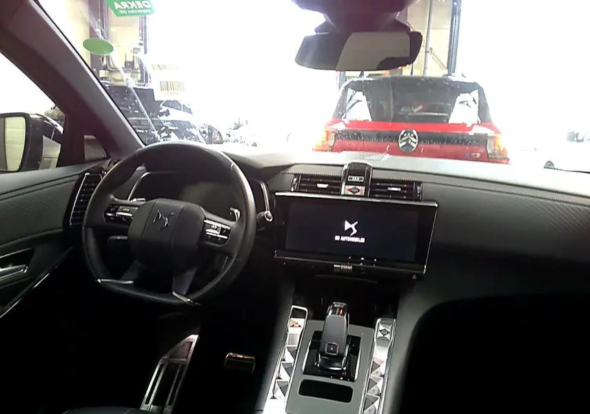 Vue intérieure avant du DS7 2025 avec tableau de bord noir, écran tactile large et volant cuir noir.