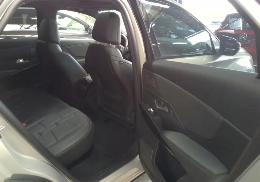 Vue intérieure côté arrière gauche du DS7 Cristal Pearl, montrant la porte ouverte et les sièges en cuir noir.