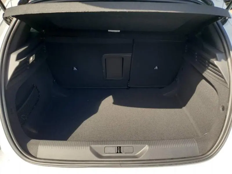 Vue intérieure du coffre ouvert d'une Peugeot 308 blanc Okénite, montrant un espace de rangement propre et spacieux.