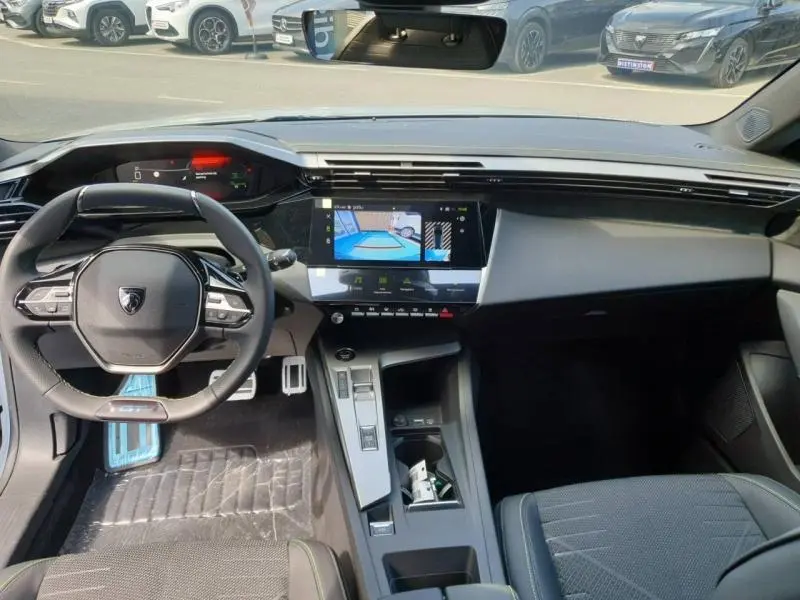 Vue intérieure avant de la Peugeot 308 Hybrid 2026, tableau de bord moderne avec écran tactile et volant compact noir.