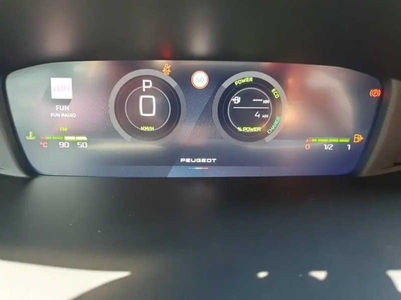 Vue rapprochée du tableau de bord numérique de la Peugeot 308 Hybrid, affichant la vitesse, autonomie et alertes.