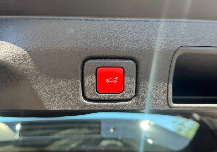 Bouton rouge d'ouverture électrique du coffre sur tableau de bord intérieur du Jeep Compass Vulcano 2026.