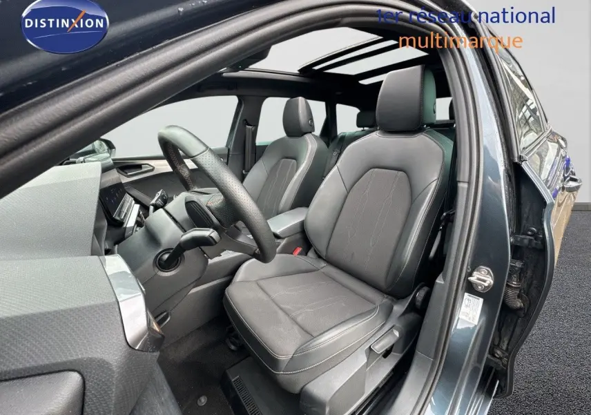 Vue intérieure côté conducteur de la CUPRA LEON ST 2024 gris magnetic metal avec sièges en cuir noir et toit panoramique.
