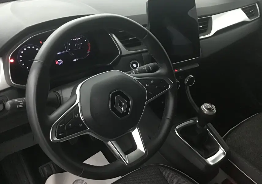 Vue rapprochée de l'intérieur du Renault Captur 2024, montrant le volant, la boîte manuelle et l'écran tactile vertical.