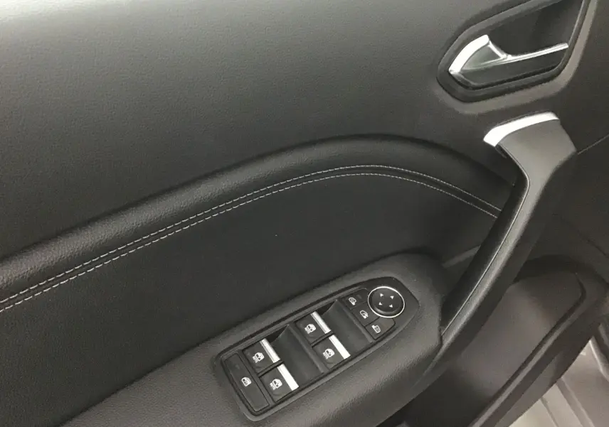 Gros plan sur la commande des vitres et la poignée intérieure côté conducteur du Renault Captur 2024 en noir.