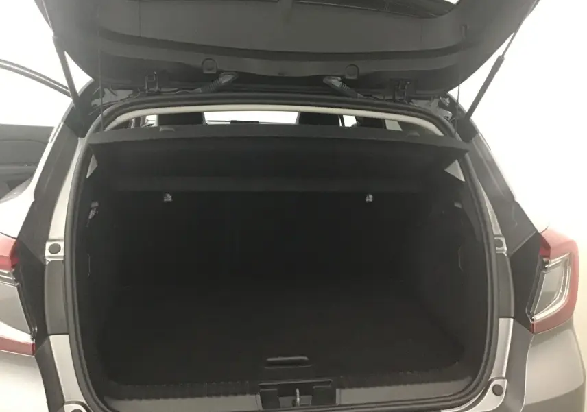 Coffre ouvert en vue arrière d'un Renault Captur gris cassiopée et noir, montrant l'espace de chargement vide.