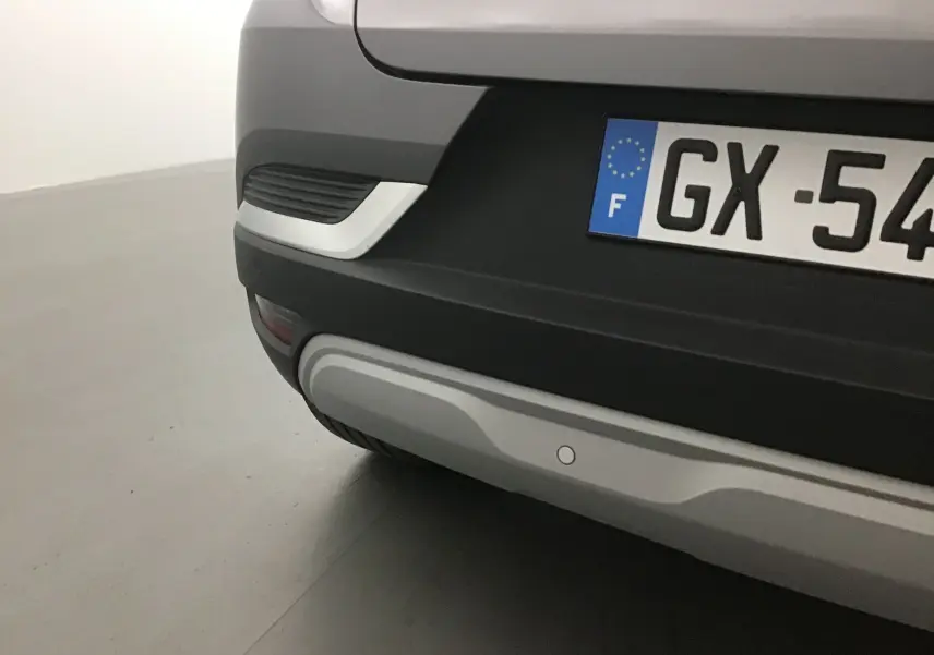 Gros plan sur le pare-chocs arrière gris cassiopée et noir du Renault Captur 2024 avec plaque d'immatriculation française.