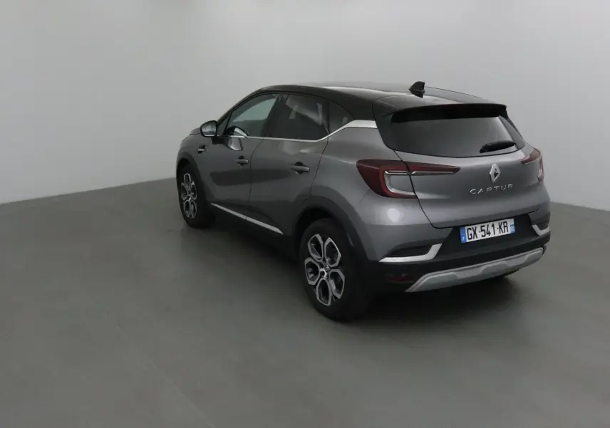 Vue 3/4 arrière droite d'un Renault Captur 2024 gris Cassiopée et noir avec jantes alliage et toit noir.