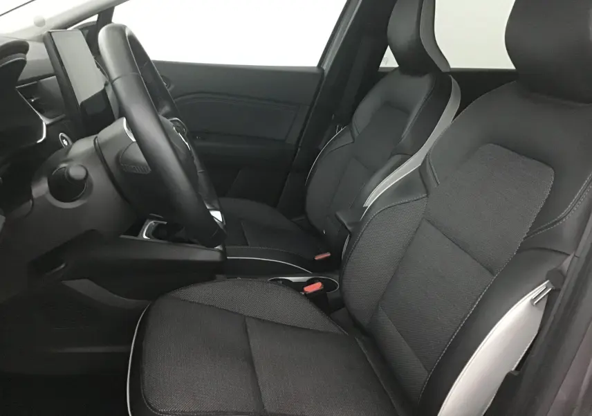 Intérieur avant du Renault Captur 2024, sièges noirs avec surpiqûres grises et tableau de bord moderne côté conducteur.