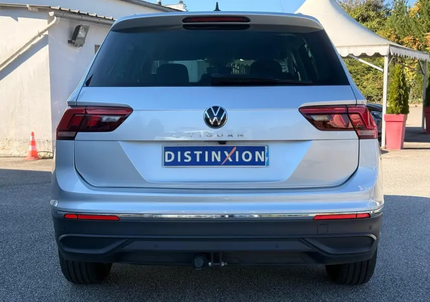 Vue arrière d'un Volkswagen Tiguan 1.5 TSI 150CH LIFE DSG7 en reflet argent avec attelage et feux LED.