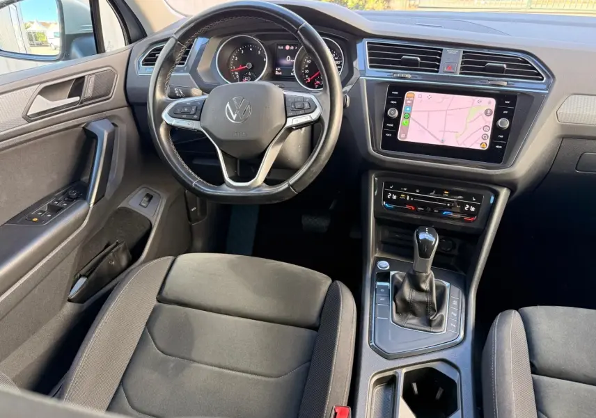 Vue intérieure du Volkswagen Tiguan 2021 côté conducteur, tableau de bord noir avec écran tactile et levier de boîte automatique.