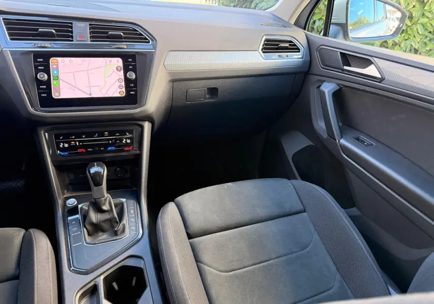 Vue intérieure côté passager du Volkswagen Tiguan 2021, mettant en valeur la console centrale et l'écran tactile.