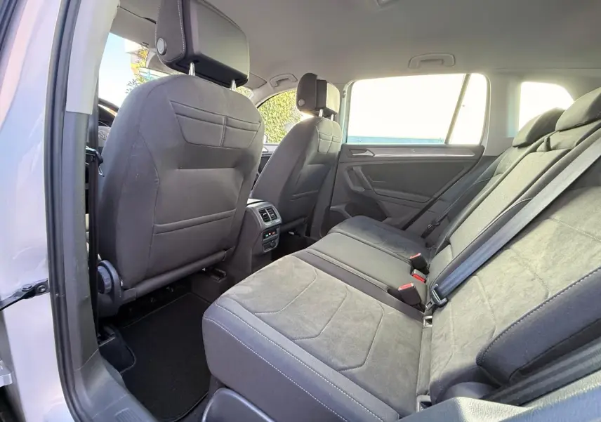Vue intérieure arrière du Volkswagen Tiguan 2021 en reflet argent, sièges arrière en tissu gris avec ceintures de sécurité visibles.